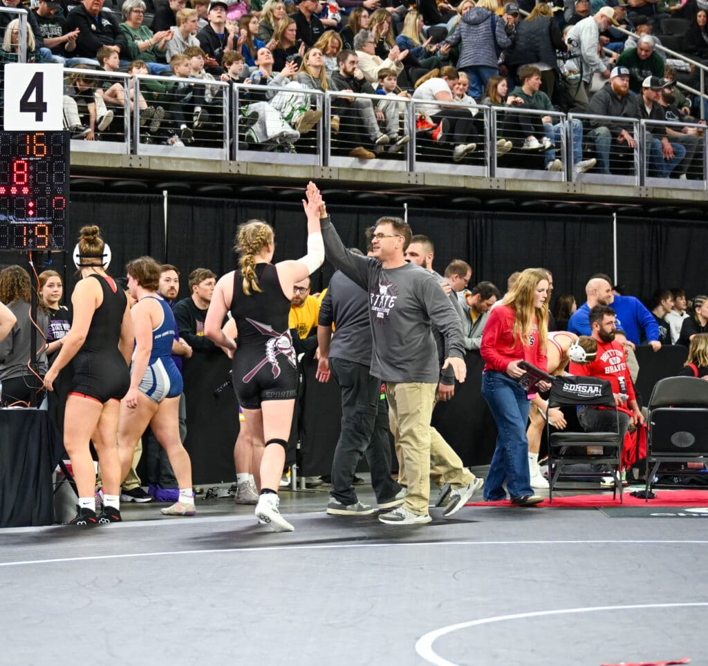 Spearfish Spartans Head Girls Wrestling Coach high fives athlete at Class AA State Wrestling Tournament in Sioux Falls.